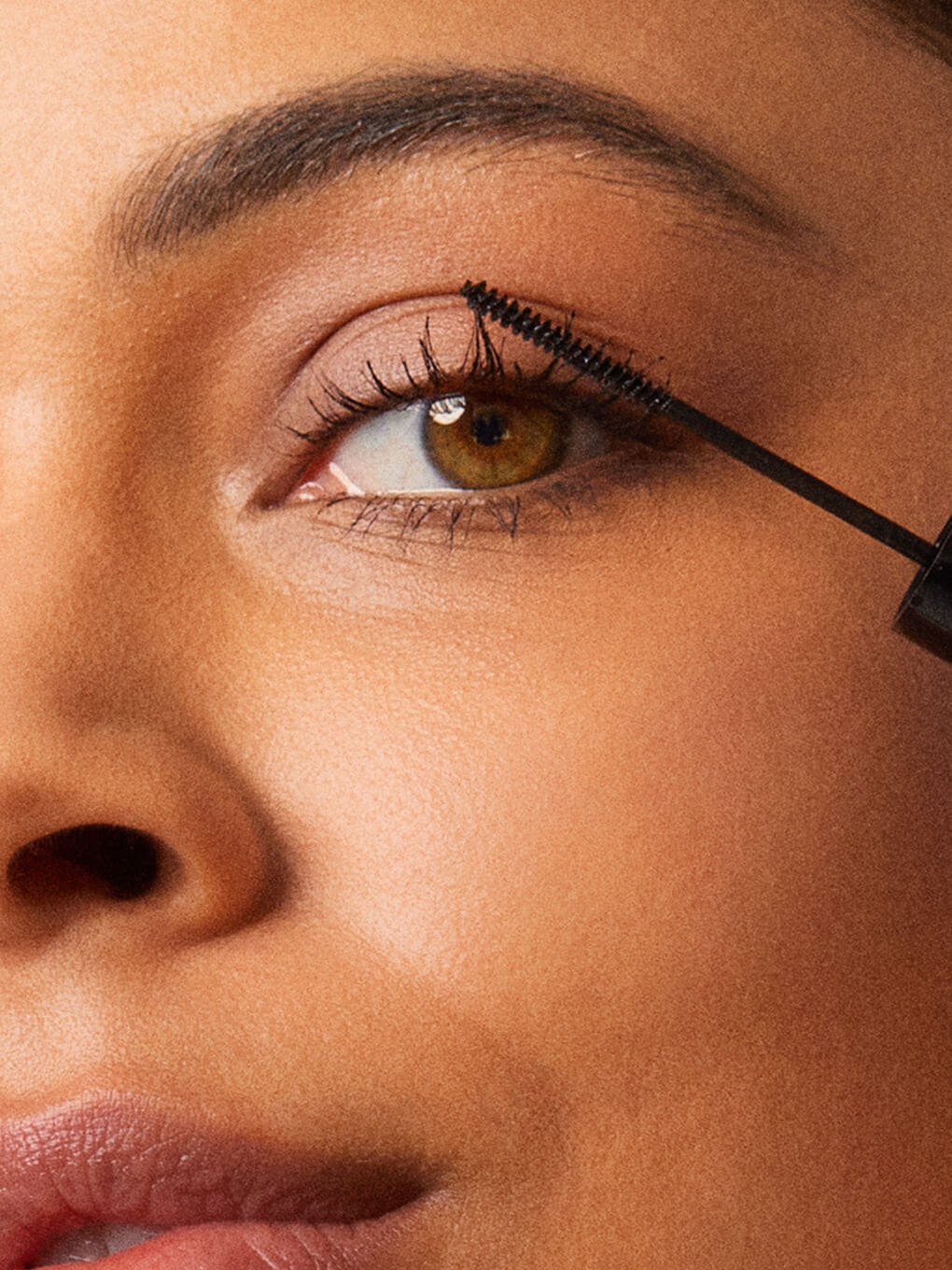 Type A Black -- close up of brunette model applying detail oriented mascara
